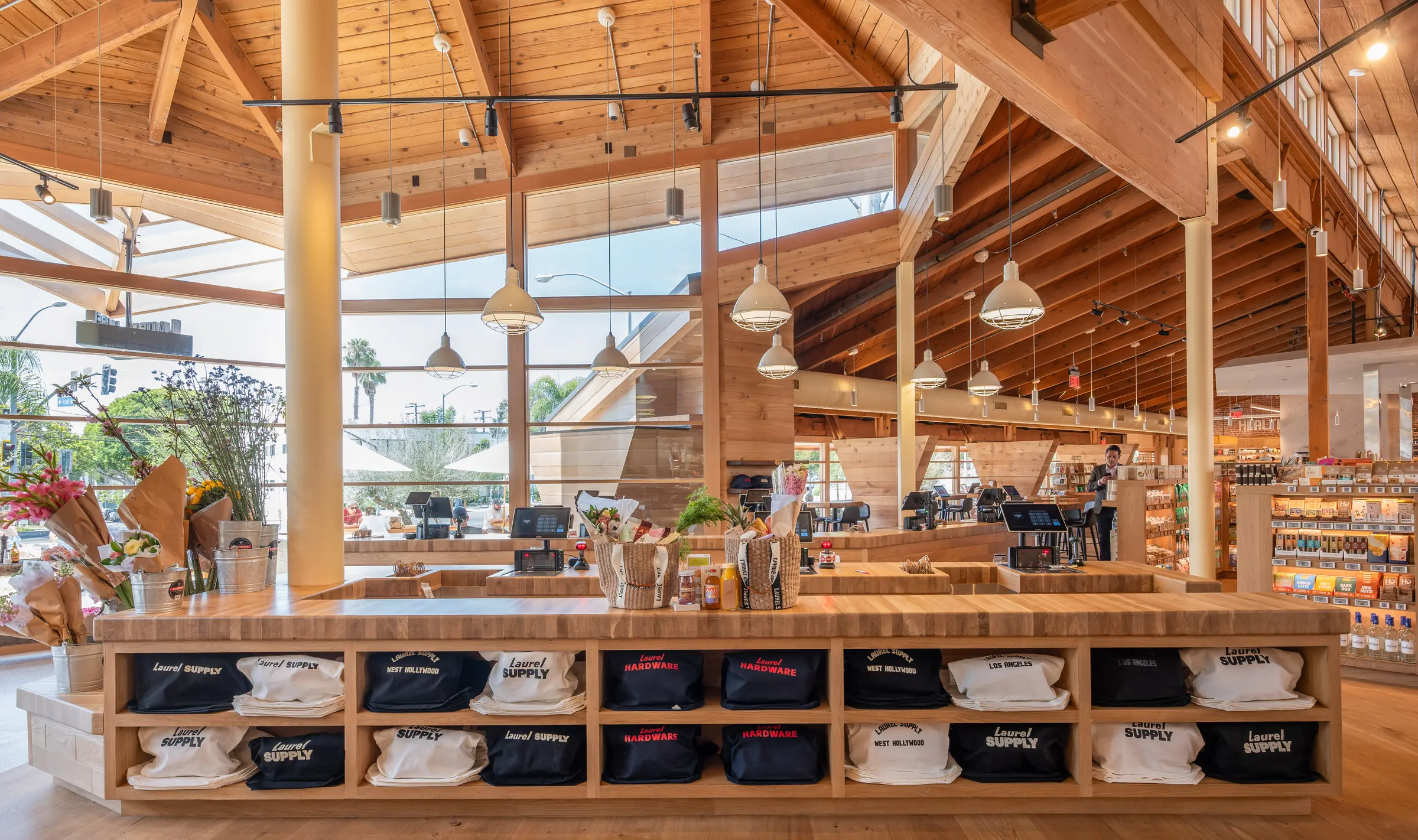 The market hall under its timber roof, with Laurel Supply totes and flowers on the counter