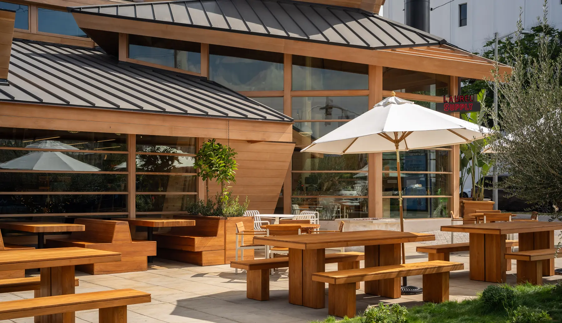 Laurel Supply's shaded patio with umbrellas, benches and planters